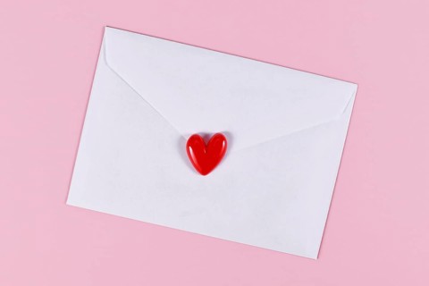 Love letter. White envelope with single red heart on pink background