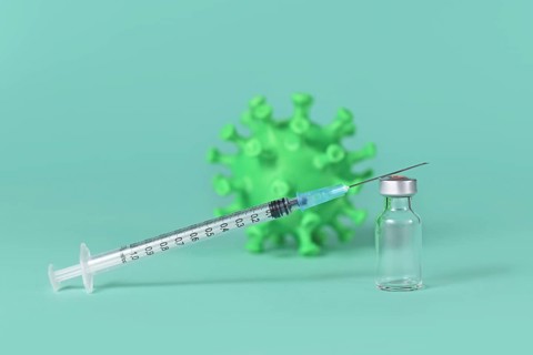Vaccine vial with syringe and corona virus model in background