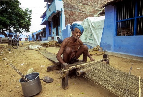 An old man weaving jute mats on the street at Tenkasi