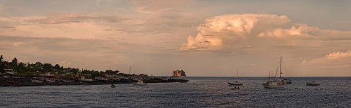Small fishing village and harbour of San Vincenzo island and Stromboli volcano at sunset and anchored sailboats