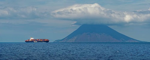 Container ship in front of the island and volcano Stromboli