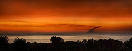 Strompoli volcano with plumes of smoke at sunset