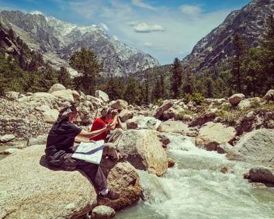 Vintage retro effect filtered hipster style image of hiker trekker tourists read a trekking map on trek in Himalayas mountains. Himachal Pradesh
