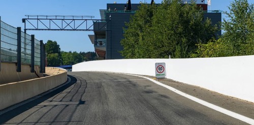 View from racing car perspective of racing driver on entrance of pit lane with sign traffic speed limit 60 km/h