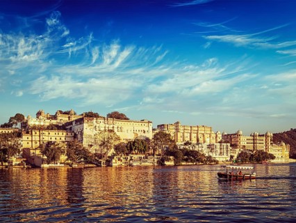 Vintage retro effect filtered hipster style image of City Palace and tourist boat on lake Pichola on sunset. Udaipur