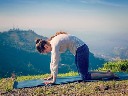 Vintage retro effect hipster style image of sporty fit woman practices yoga asana Marjariasana
