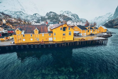 Panorama of Nusfjord authentic fishing village with yellow rorbu houses in Norwegian fjord in winter. Lofoten islands