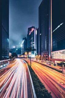Street traffic in Hong Kong at night. Office skyscraper buildings and busy traffic on highway road with blurred cars light trails. Hong Kong