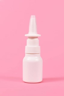 White nasal spray bottle on pink background