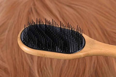 Detangler hair brush with different bristle lengths to separate hair instead of pulling it down