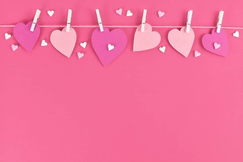 Pink paper hearts hanging from line with pegs and sugar sprinkles