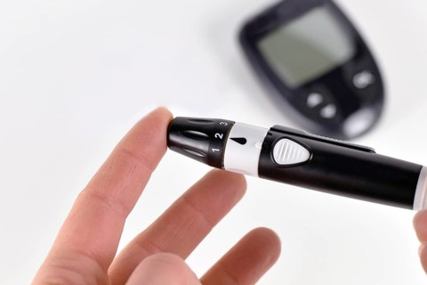 Pricking finger with lancing device used by diabetic person for checking blood glucose sugar level