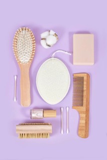 Eco friendly wooden beauty and hygiene products like comb and soap arranged on violet background