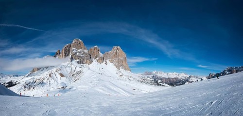 Panoramaof a ski resort piste with people skiing in Dolomites in Italy