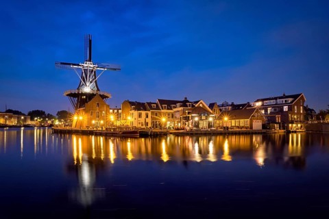 View of Harlem cityscape with landmark windmill De Adriaan on Spaarne river in the night illuminated. Harlem