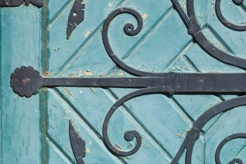Old decorated iron door fitting on an old green wooden door
