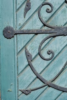 Old decorated iron door fitting on an old green wooden door