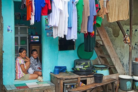 Indonesian mother and daughter at home with laundry drying on clothesline in Kota