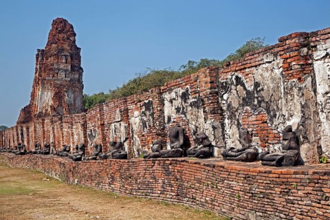 Ruin of a Buddhist stupa with a row of broken Buddha statues at Wat Mahathat in Ayutthaya Historical Park