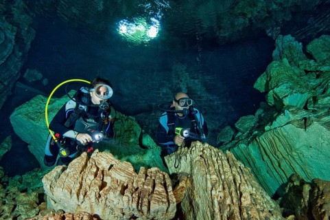 Diver under water in cave entrance of a freshwater cave