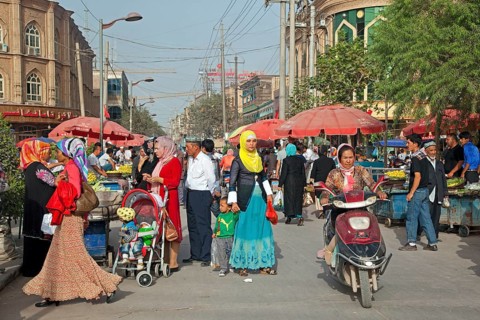 Uighur Muslim woman in Islamic dress in a shopping street in the city of Kashgar