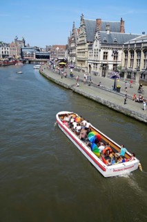 Sightseeing boat with tourists on the river Lys with a view of the guild houses on Graslei