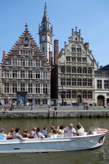 Sightseeing boat with tourists on the river Lys with a view of the guild houses on Graslei