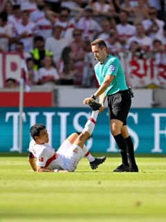 Referee Tobias Stieler helps Wataru Endo VfB Stuttgart