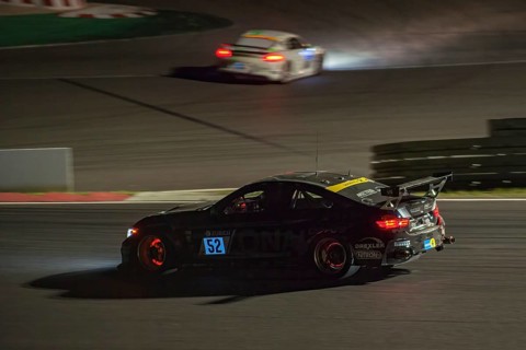 Race car BMW M4 at night during car race 24-hour race 24h race on Grand Prix track of Nuerburgring race track with glowing brake discs