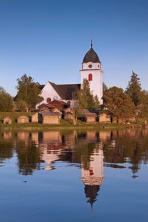 The picturesque old church of Raettvik surrounded by horse stables at Lake Siljan