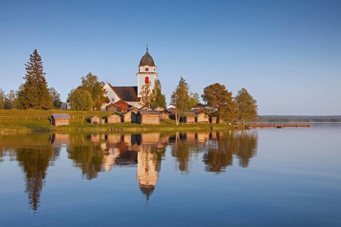The picturesque old church of Raettvik surrounded by horse stables at Lake Siljan