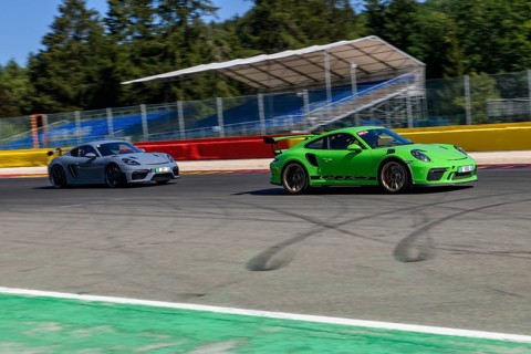 Racing car sports car right Porsche GT3 overtakes left Porsche Cayman GT4 races at high speed full throttle at exit of bend hairpin La Source of racetrack