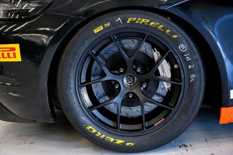 Racing tyres with markings of racing mechanic lettering mounted on racing car in pit of racetrack for car racing