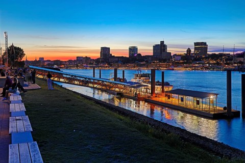 Pier for the harbour ferries at the Stage Theater on the Elbe in the evening in front of the city skyline