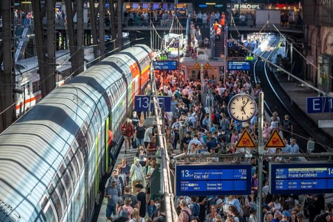 Many people standing crowded on a platform in front of a local train