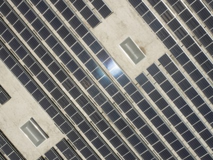 Aerial view of solar panels mounted on roof of large industrial building or warehouse