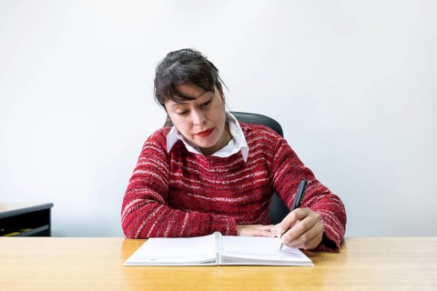 Latin business woman sitting at her desk taking notes