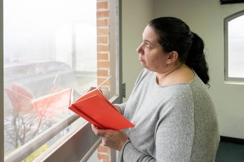 Business woman holding her notebook and pencil looking pensively out the office window