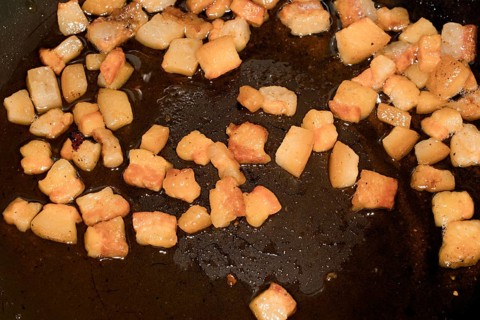 Pancetta cubes are fried in a pan