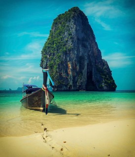 Long tail boat on tropical beach with limestone rock