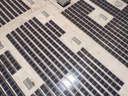 Aerial view of solar panels mounted on roof of large industrial building or warehouse