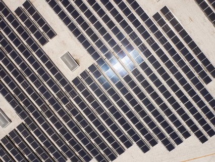 Aerial view of solar panels mounted on roof of large industrial building or warehouse