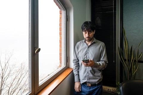 Latino businessman working in an office overlooking the river using the phone