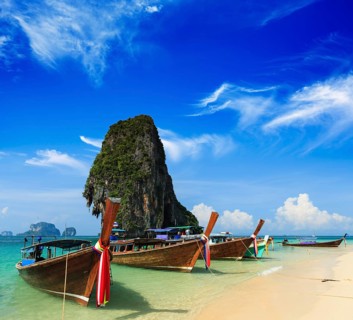 Long tail boat on tropical beach with limestone rock