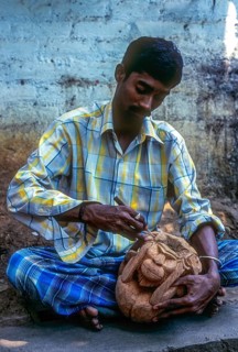 A man carving monkey on the shell of coconut