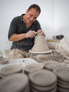 Moroccan potter at work: turning at the potter's pane and shaping ceramic vessels and pottery: Jugs