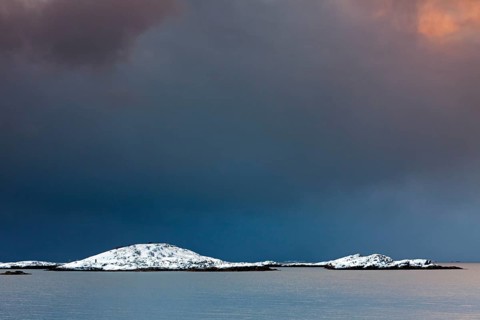 Storm clouds over Bergen in the snow in winter at the fjord of Henningsvaer