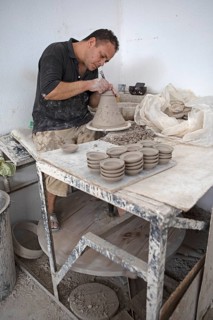 Moroccan potter at work: turning at the potter's pane and shaping ceramic vessels and pottery: Jugs
