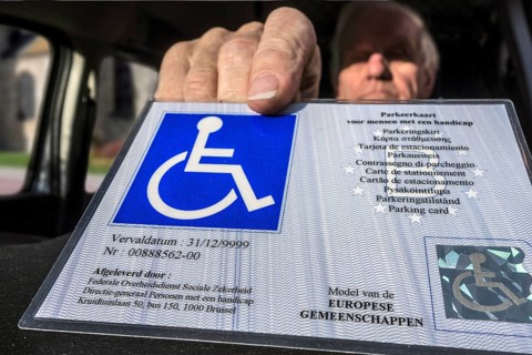 Disabled elderly man puts EU parking card for people with disabilities