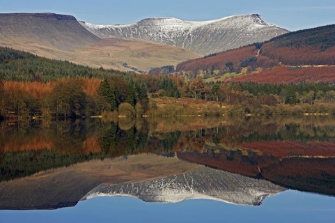 Trees and snow-capped hills reflected in the reservoir